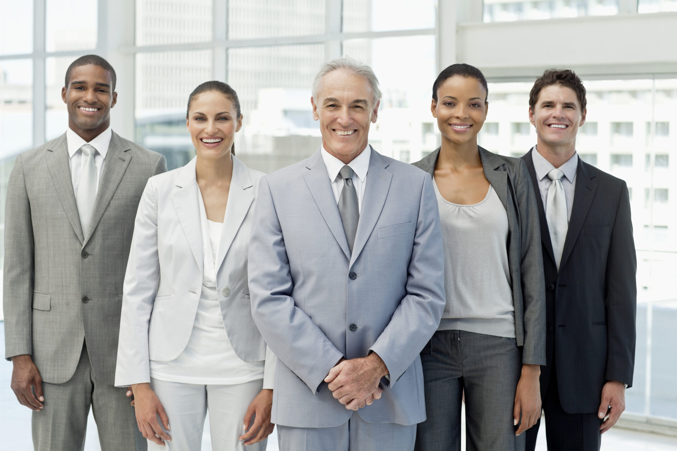 Handsome mature businessman and his team smile while posing for the camera in an office building. Horizontal shot.